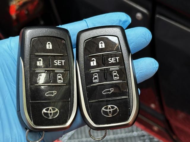 青い手袋の手に並べたトヨタのスマートキー2本。